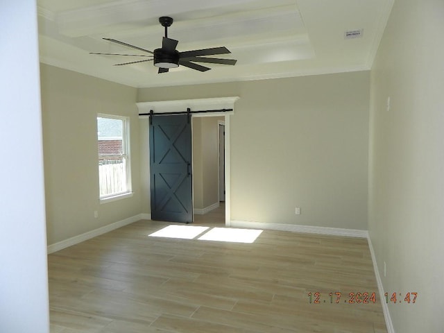 empty room with ceiling fan, light hardwood / wood-style flooring, and a barn door