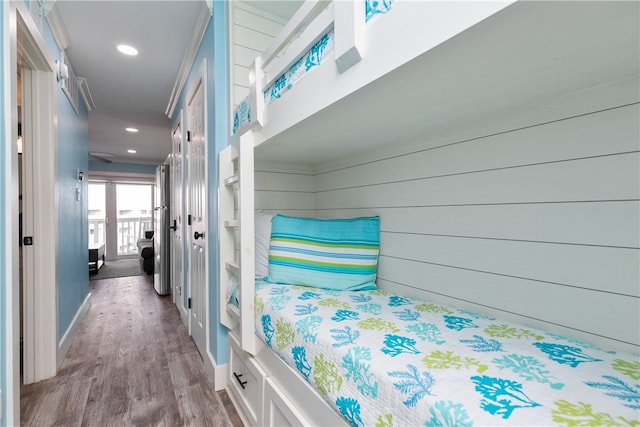 bedroom featuring wood walls, light wood-type flooring, and ornamental molding