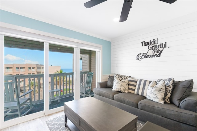 living room featuring ornamental molding, light wood-type flooring, and ceiling fan