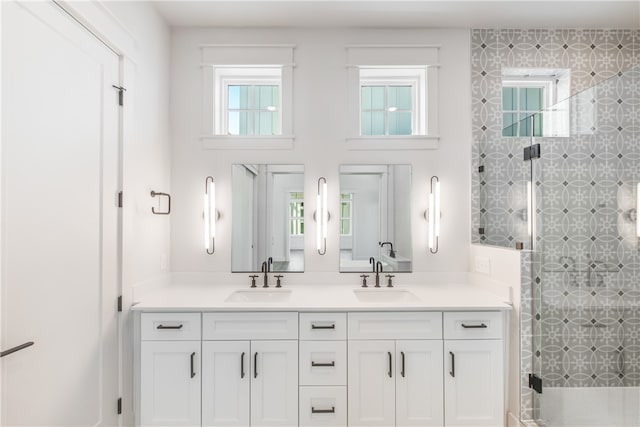 bathroom featuring a shower with shower door and vanity