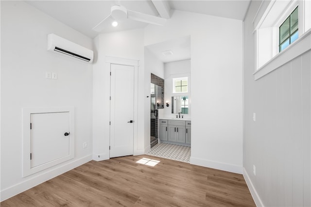 foyer entrance featuring sink, light wood-type flooring, a wall unit AC, and vaulted ceiling