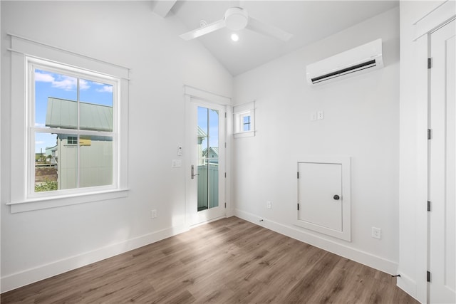 unfurnished room with hardwood / wood-style floors, plenty of natural light, lofted ceiling, and a wall mounted air conditioner