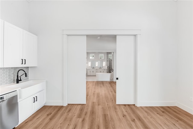 interior space featuring white cabinets, light hardwood / wood-style floors, dishwasher, and tasteful backsplash