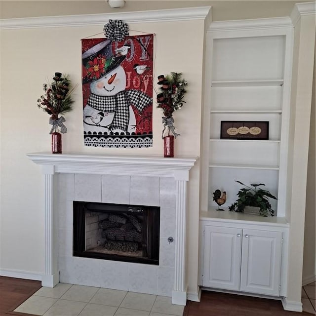 details with hardwood / wood-style floors, built in shelves, ornamental molding, and a tiled fireplace