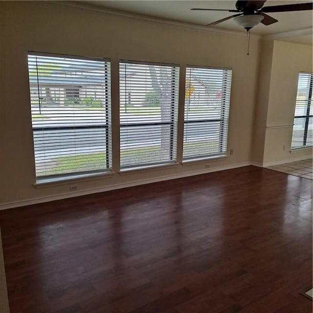 empty room featuring dark hardwood / wood-style flooring, a wealth of natural light, ornamental molding, and ceiling fan