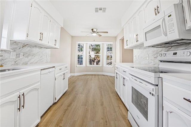 kitchen with light hardwood / wood-style floors, backsplash, white appliances, and white cabinets