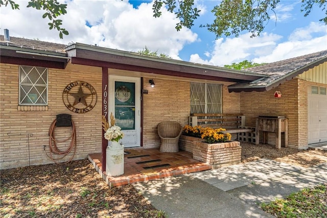 10637 Westwood Dr, Corpus Christi, TX 78410 - doorway to property featuring brick siding, an attached garage, and roof with shingles