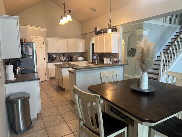 6333 Oso Pkwy, Corpus Christi, TX 78414 - kitchen with dark countertops, decorative backsplash, high vaulted ceiling, decorative light fixtures, and white cabinets