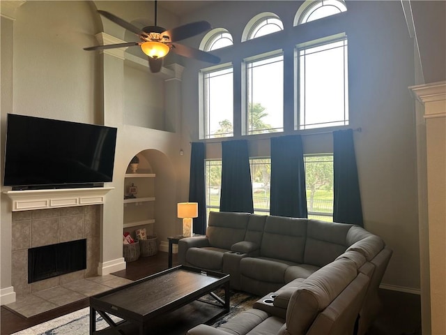 6333 Oso Pkwy, Corpus Christi, TX 78414 - living room with a towering ceiling, a tile fireplace, built in shelves, a ceiling fan, and baseboards
