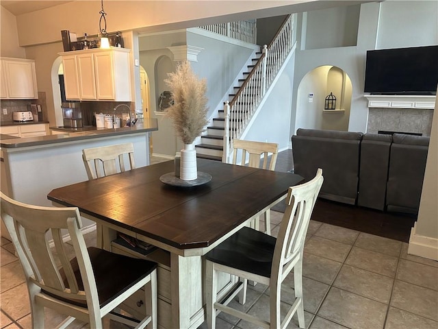 6333 Oso Pkwy, Corpus Christi, TX 78414 - dining area featuring light tile patterned flooring, stairway, arched walkways, and a tiled fireplace
