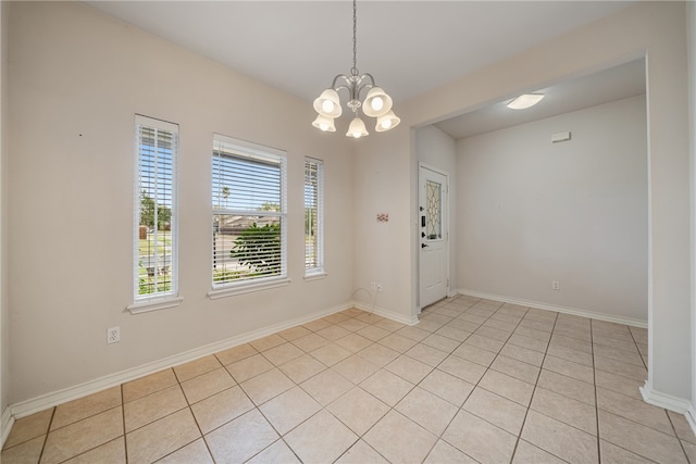 tiled spare room with a chandelier