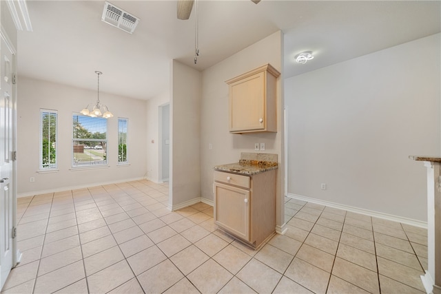 kitchen featuring light brown cabinets, light stone counters, decorative light fixtures, light tile patterned flooring, and ceiling fan with notable chandelier