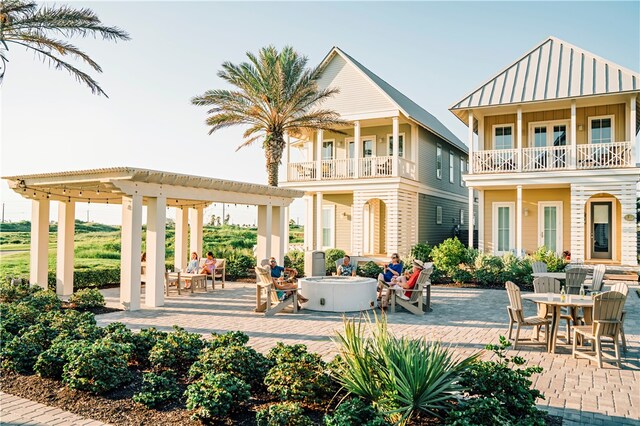 rear view of property with a balcony, a patio, a fire pit, and a pergola