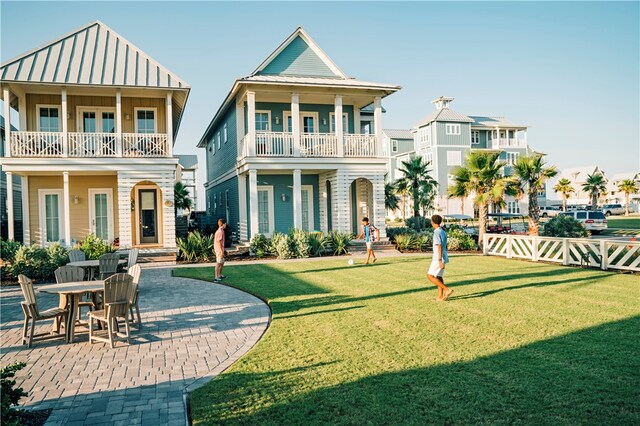 exterior space featuring a front lawn, a balcony, and a patio