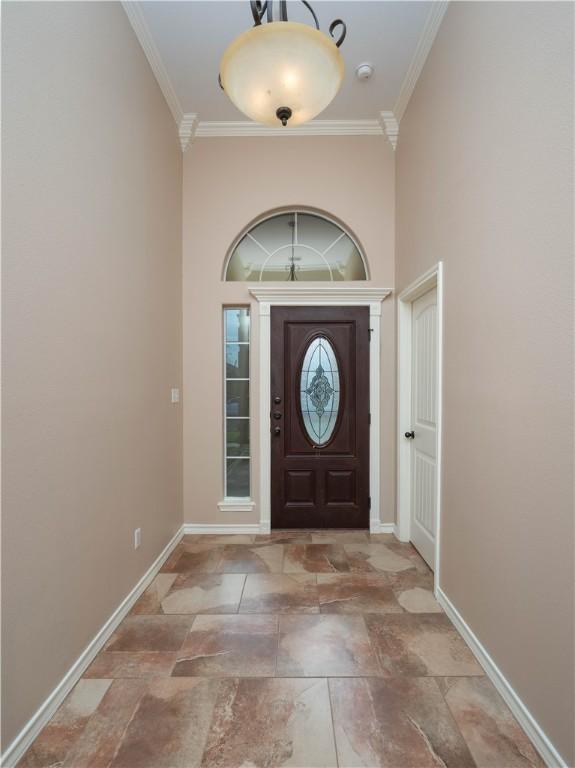 foyer with crown molding and baseboards