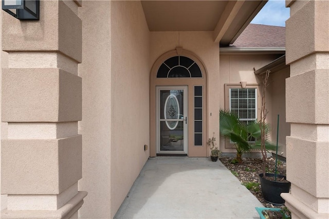 entrance to property with roof with shingles and stucco siding