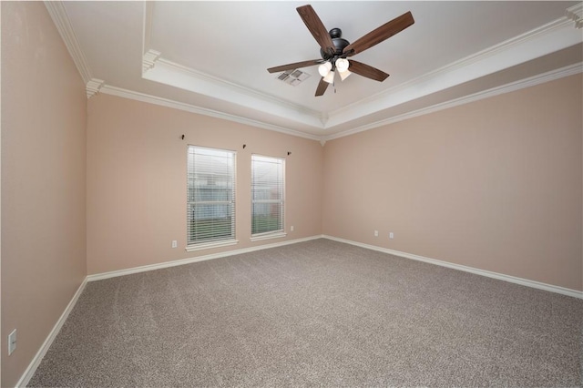 carpeted empty room with baseboards, visible vents, ceiling fan, a tray ceiling, and crown molding