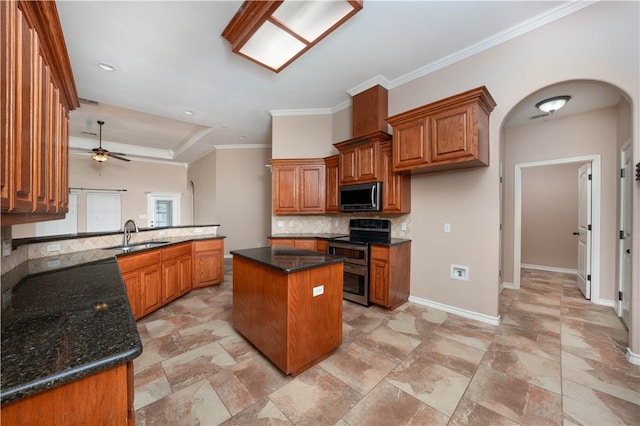 kitchen with arched walkways, a sink, appliances with stainless steel finishes, decorative backsplash, and brown cabinetry