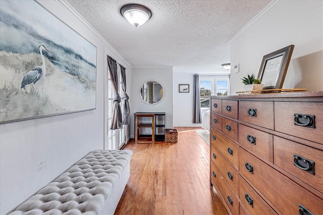 bedroom with ornamental molding, a textured ceiling, and light hardwood / wood-style floors