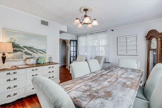 bedroom featuring a textured ceiling, ornamental molding, dark hardwood / wood-style floors, and a notable chandelier