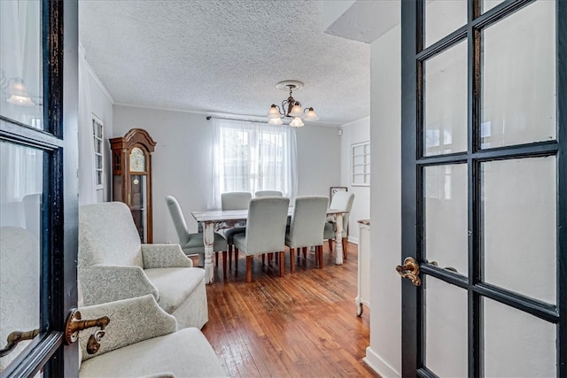 interior space featuring ornamental molding, a textured ceiling, wood-type flooring, and a chandelier