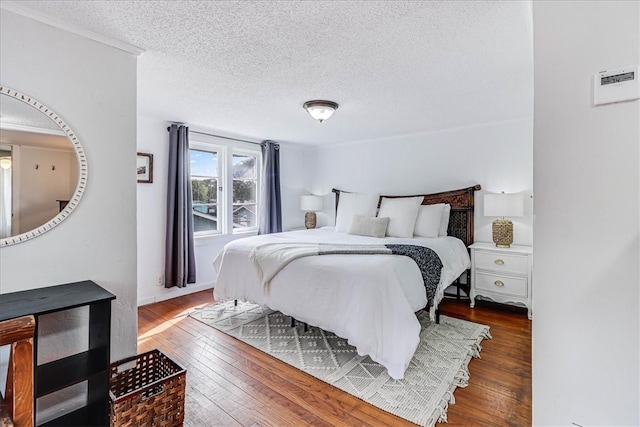 bedroom with a textured ceiling and dark hardwood / wood-style floors