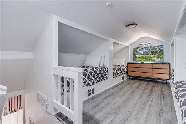 bedroom with light wood-type flooring and lofted ceiling