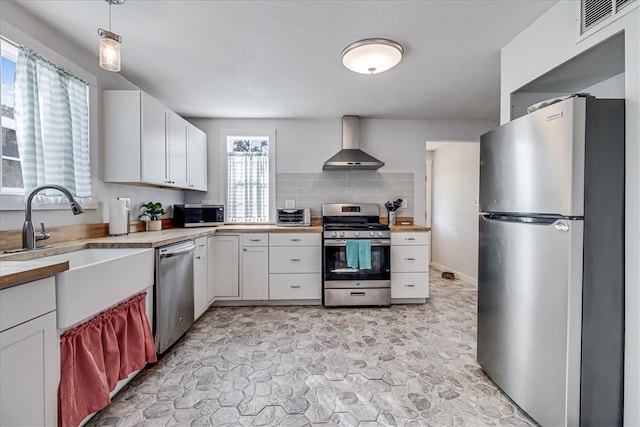 kitchen featuring white cabinetry, appliances with stainless steel finishes, sink, and wall chimney exhaust hood