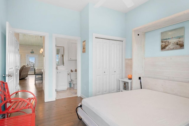 bedroom with a closet, baseboards, ensuite bath, and hardwood / wood-style floors