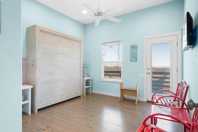 sitting room with a ceiling fan, recessed lighting, wood-type flooring, and baseboards