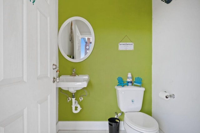 bathroom featuring toilet, tile patterned flooring, baseboards, and a sink