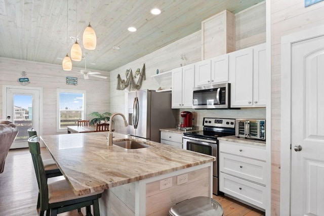 kitchen with a sink, white cabinetry, a kitchen breakfast bar, appliances with stainless steel finishes, and an island with sink