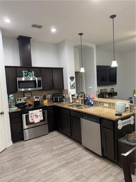 kitchen featuring pendant lighting, sink, kitchen peninsula, and appliances with stainless steel finishes