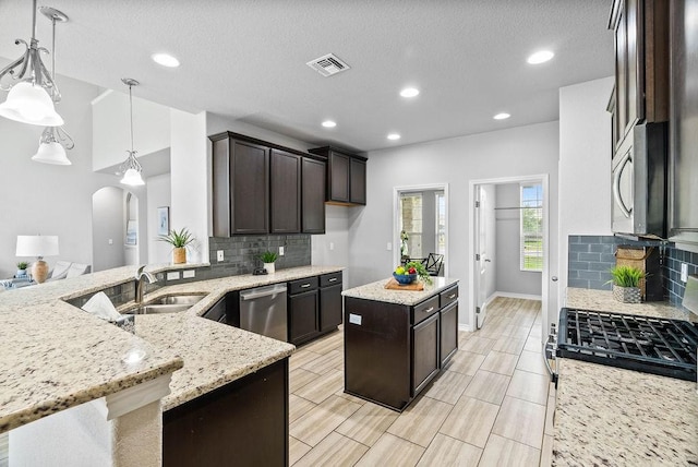 2530 Las Estrellas St, Corpus Christi, TX 78414 - kitchen with appliances with stainless steel finishes, arched walkways, dark brown cabinetry, tasteful backsplash, and recessed lighting