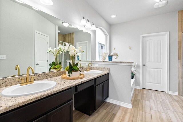 2530 Las Estrellas St, Corpus Christi, TX 78414 - bathroom featuring double vanity, a tile shower, and wood finished floors