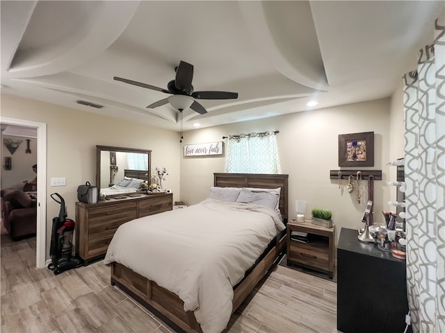 bedroom with ceiling fan, multiple windows, and light hardwood / wood-style flooring