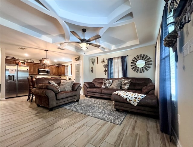 living room with light wood-type flooring, coffered ceiling, and ceiling fan with notable chandelier