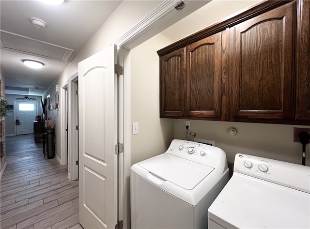 clothes washing area with cabinets, independent washer and dryer, and light hardwood / wood-style flooring