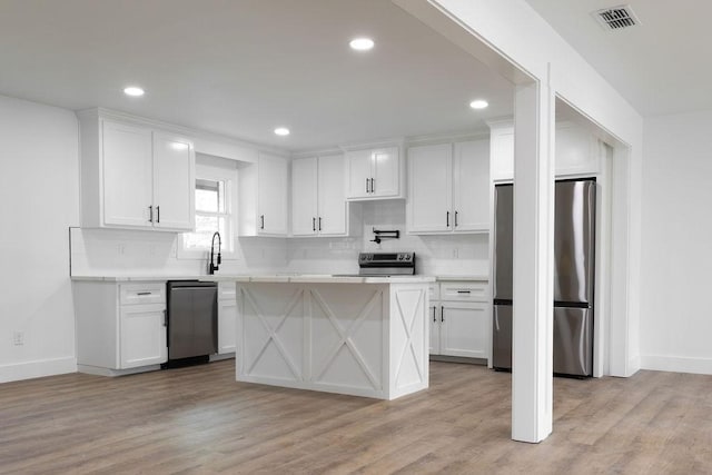 1101 Lillian St, Alice, TX 78332 - kitchen with appliances with stainless steel finishes, light countertops, white cabinets, decorative backsplash, and recessed lighting