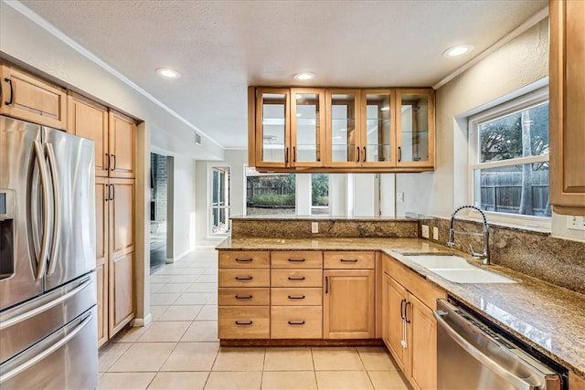 kitchen featuring appliances with stainless steel finishes, sink, ornamental molding, light tile patterned flooring, and light stone counters