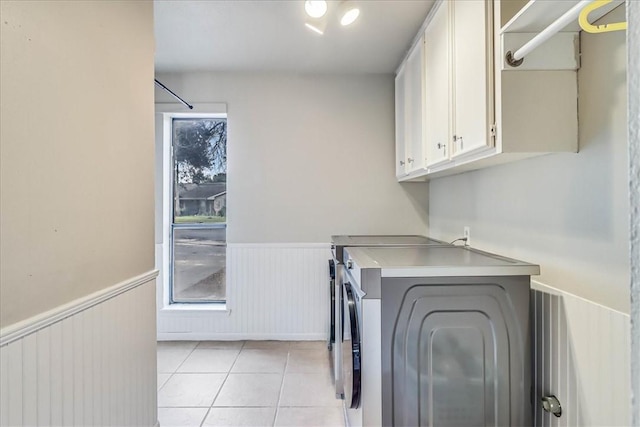 laundry area with light tile patterned flooring, washer and dryer, and cabinets