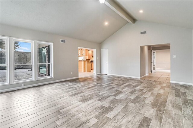 unfurnished living room featuring high vaulted ceiling and beam ceiling