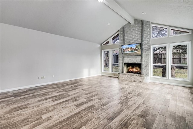 unfurnished living room with hardwood / wood-style flooring, a brick fireplace, high vaulted ceiling, a textured ceiling, and beamed ceiling