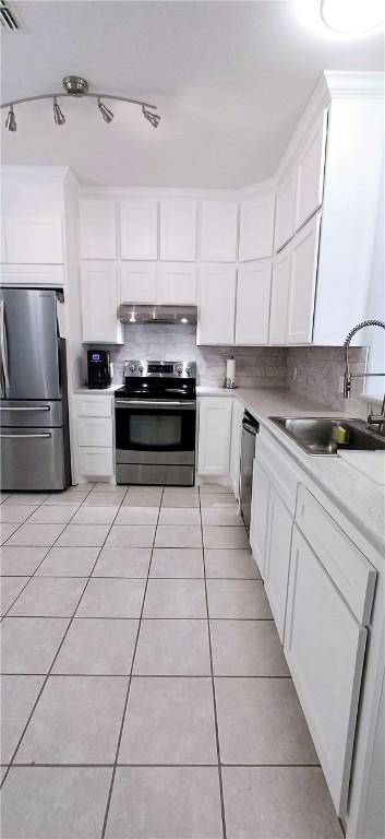 13829 Suntan Ave, Corpus Christi, TX 78418 - kitchen with appliances with stainless steel finishes, under cabinet range hood, white cabinetry, light tile patterned floors, and decorative backsplash