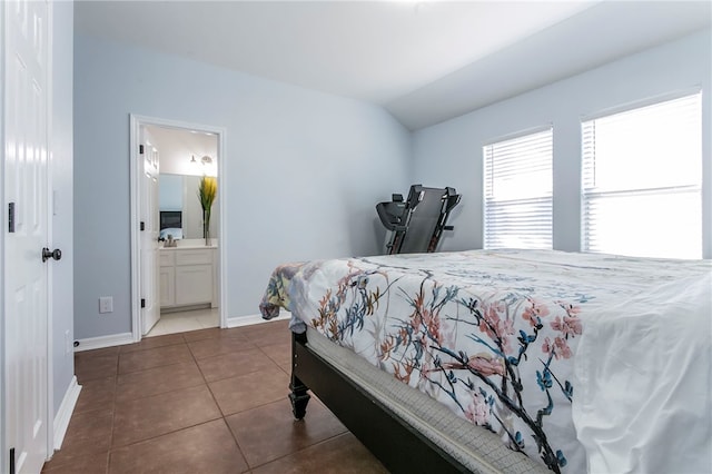 tiled bedroom featuring ensuite bath and vaulted ceiling