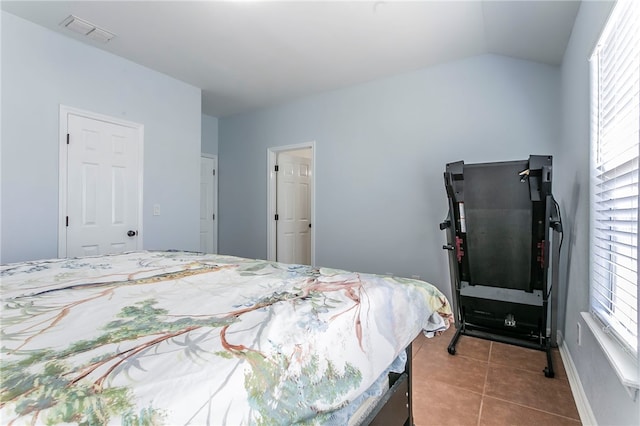 tiled bedroom featuring vaulted ceiling