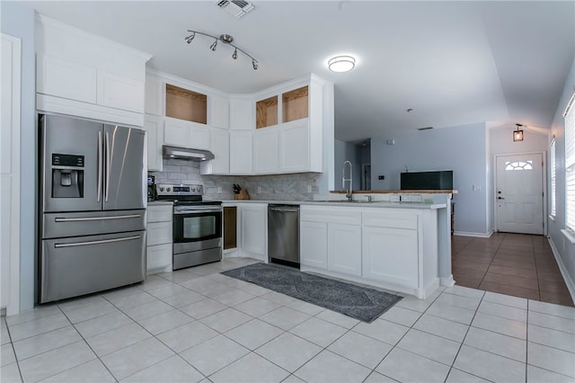 kitchen with white cabinetry, tasteful backsplash, kitchen peninsula, exhaust hood, and appliances with stainless steel finishes