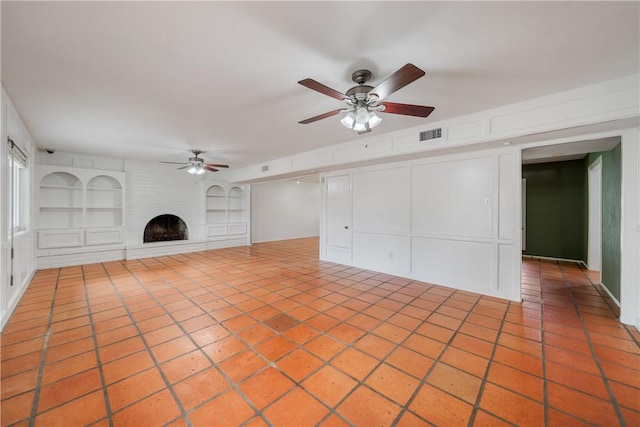 5049 Moultrie Dr, Corpus Christi, TX 78413 - unfurnished living room with ceiling fan, built in shelves, a brick fireplace, tile patterned floors, and a decorative wall