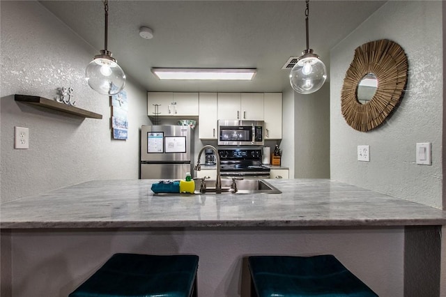 kitchen featuring appliances with stainless steel finishes, pendant lighting, white cabinetry, and kitchen peninsula