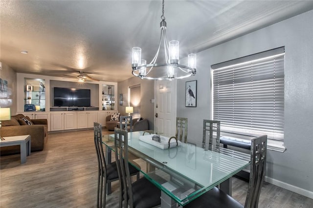 dining space with ceiling fan with notable chandelier and wood-type flooring